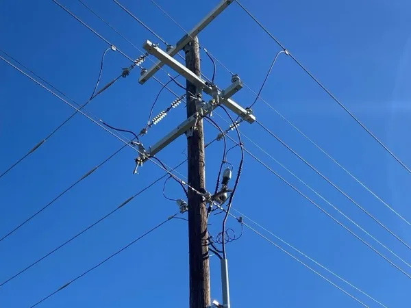 New crossarm, insulators and taps on a pole seen from below against a clear sky