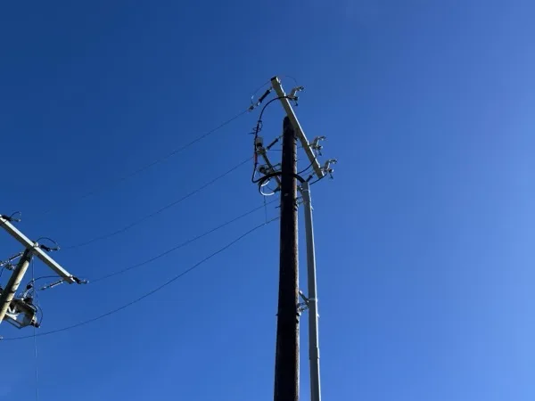 Riser pole with pole top terminations and a conduit riser against a clear blue sky