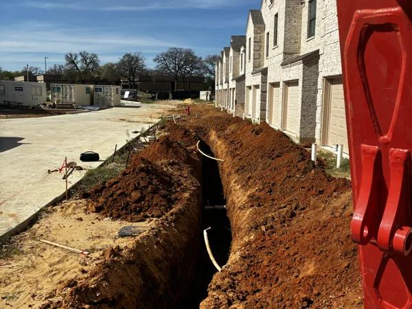 Trench with conduit laid along the townhome buildings