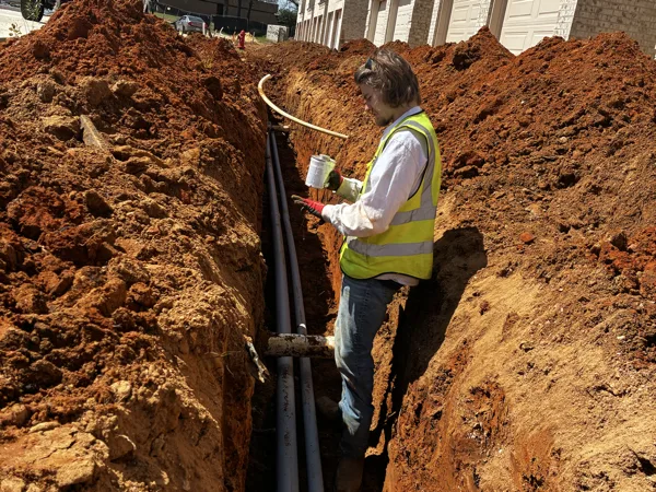 Electrician in a trench working on the conduit run
